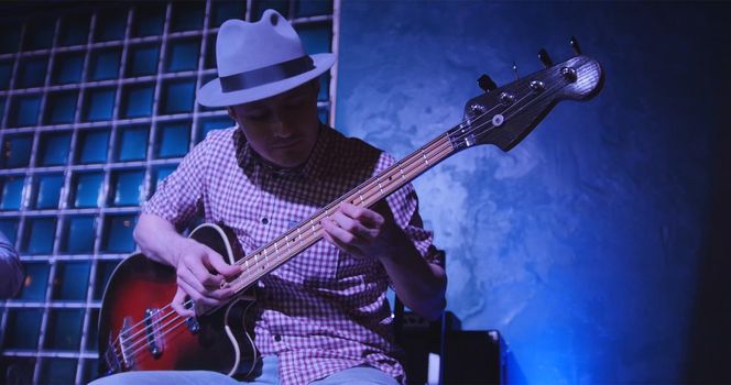 Guitarist at scene in bar - musician in hat plays guitar, close up