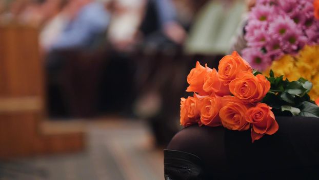 Audience in the concert hall holding flowers and applauding the performance on stage, telephoto