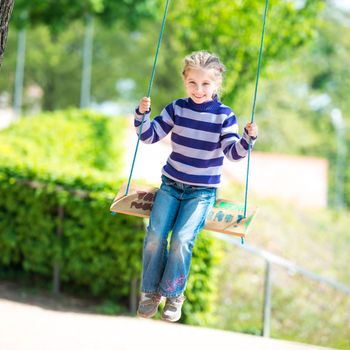 happy little girl on swing in park