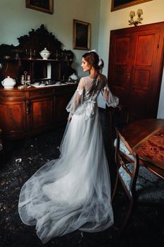 a bride in underwear and a white robe in the interior of a Villa in Italy at a wedding.morning of the bride in Tuscany.boudoir photo session at the Villa