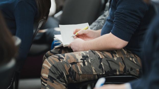 People - sitting and listen to the conference or presentation, workshop, master class - notes and pens, telephoto