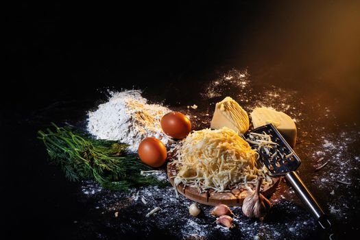 still life of the process of making cheese balls with garlic and dill on a black background.