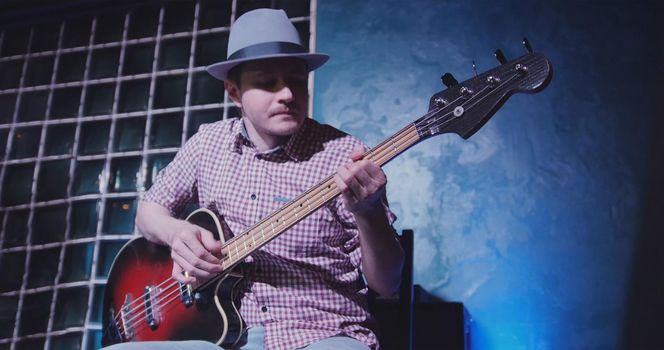 Guitarist in hat at scene in bar - musician plays guitar, close up