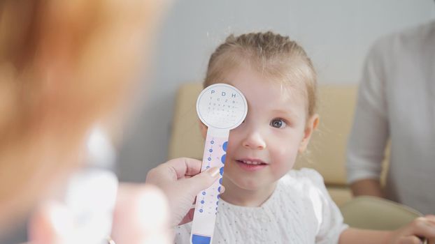 Check up of eyesight in child's ophthalmology - optometrist diagnosis little girl, close up