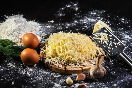 still life of the process of making cheese balls with garlic and dill on a black background.