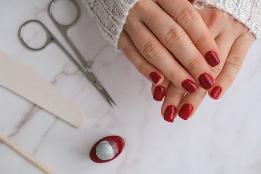 Stylish red female nails. Modern Beautiful manicure. Autumn winter nail design concept of beauty treatment. Gel nails. Skin care. Wellness. Trendy colors.