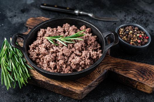 Fried mince beef meat in a pan for cooking pasta. Black background. Top view.