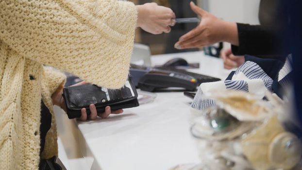 Woman paying by credit card in dress store - trading concept, close up