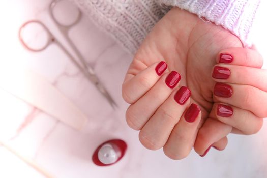 Stylish red female nails. Modern Beautiful manicure. Autumn winter nail design concept of beauty treatment. Gel nails. Skin care. Wellness. Trendy colors.