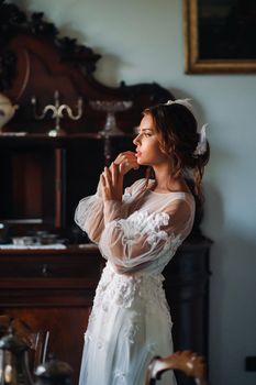 a bride in underwear and a white robe in the interior of a Villa in Italy at a wedding.morning of the bride in Tuscany.boudoir photo session at the Villa