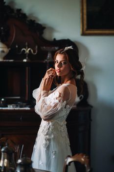 a bride in underwear and a white robe in the interior of a Villa in Italy at a wedding.morning of the bride in Tuscany.boudoir photo session at the Villa