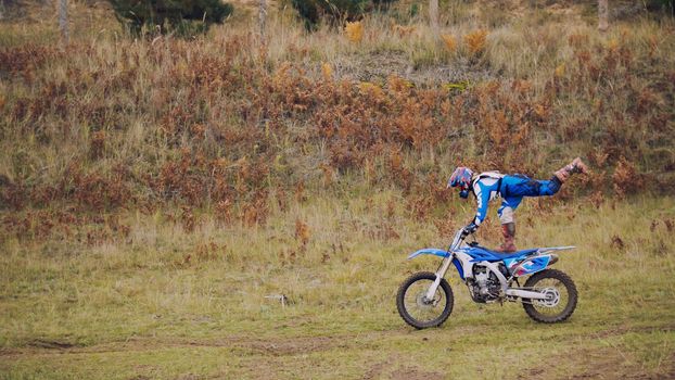 MX moto woman Biker shows acrobatic at cross racing - rider on a dirt motorcycle, telephoto