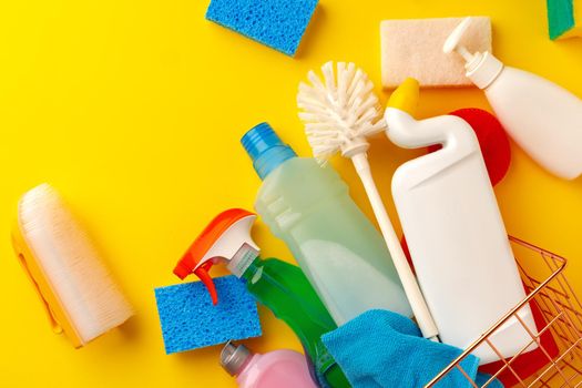 Set of cleaning supplies on yellow color background, top view
