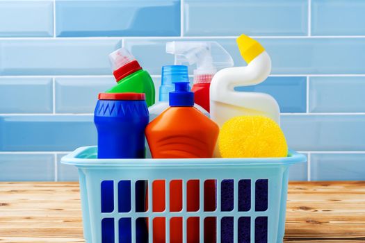 Household detergents and cleaning tools against blue tile background, close up