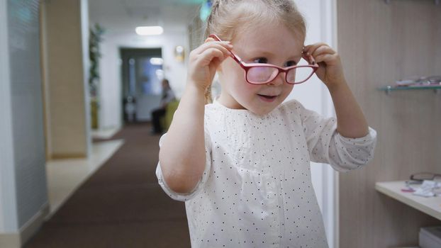 Blonde little girl in glasses in hall of ophthalmology clinic - medical, portrait