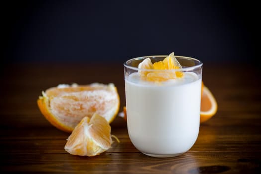 homemade sweet yogurt in a glass with oranges on a wooden table