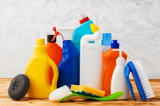 Household cleaning detergents on wooden table against gray background, close up