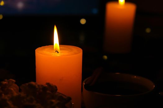 Movie on laptop at night in bedroom lit with candles. Pop corn. Autumn atmosphere at home. Cozy hygge style