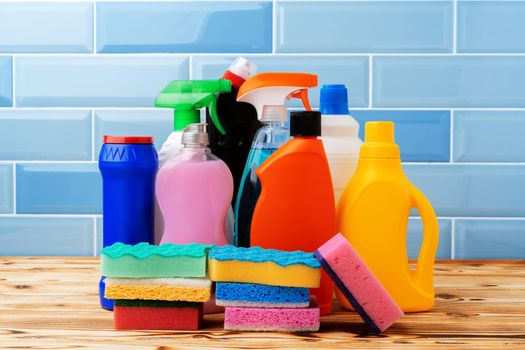 Household detergents and cleaning tools against blue tile background, close up