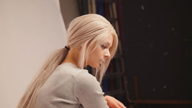Blonde model posing for photographer at studio, telephoto