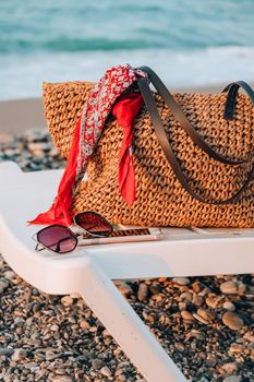 Sun loungers with bag sunglasses and mobile phone in front of sea. Sun chairs on sandy beach. Chaise longue and folded umbrella stand at the edge of the seaSummertime vacation