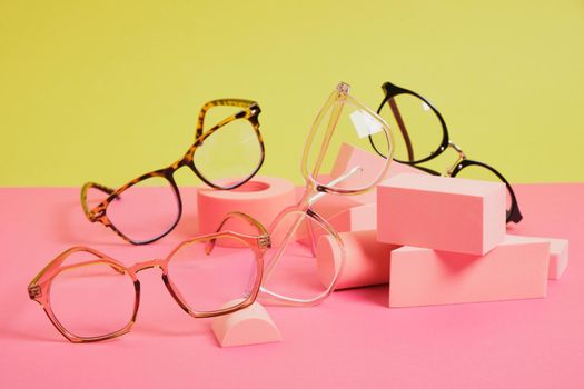 several different trendy eye glasses on geometric pink podiums, colorful background, copy space