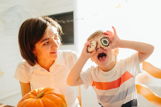 Happy halloween. Young beautiful mother and her son carving pumpkin. Happy family preparing for Halloween. Happy Halloween concept .