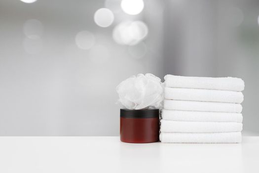 Spa still life with towels and skincare cosmetics against blurred background, close up