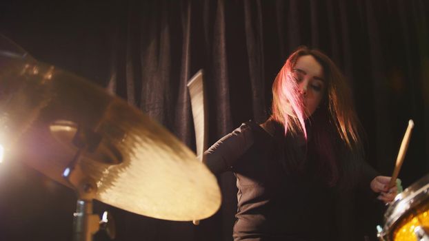 Flowing black hair - beauty girl plays drum rock at garage, close up