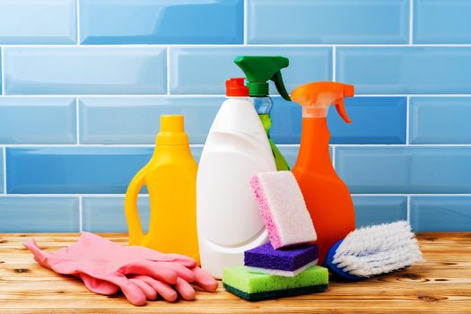 Household detergents and cleaning tools against blue tile background, close up