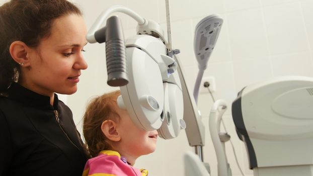 Mother and little girl - optometrist Checks Child's Eye - Children ophthalmology, close up