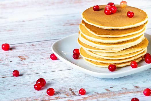 morning breakfast pancakes with cranberries on a wooden table in a plate.