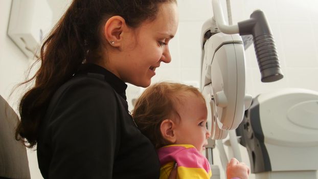 Children ophthalmology - mother and little girl - optometrist Checks Child's Eye, close up