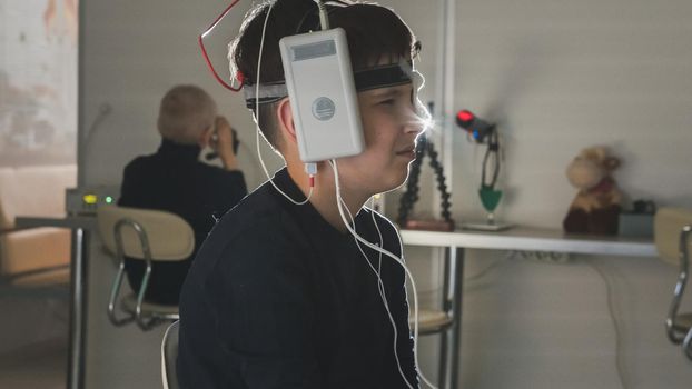 Teenager boy with electrodes on the head looking to monitor - healthcare children's diagnostic - Ophthalmology researching, close up