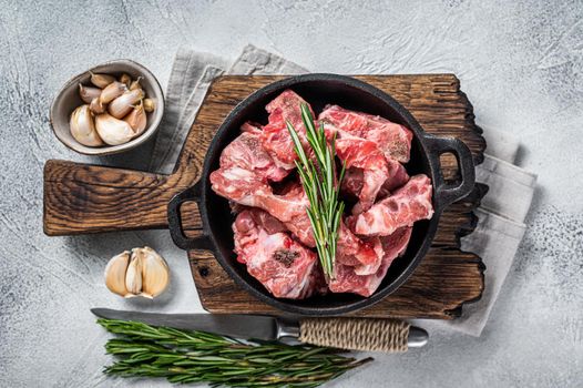 Raw diced meat cubes with bone in a pan. White background. Top View.