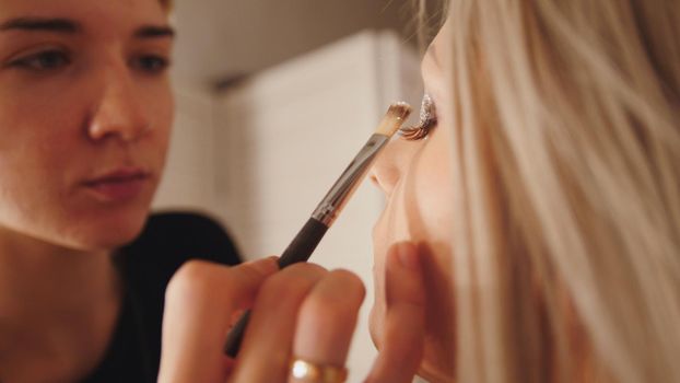 Makeup artist makes handsome models eye makeup, close up