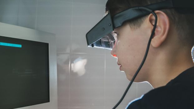 Ophthalmology - child boy checks eyes with stereo glasses and monitor, close-up