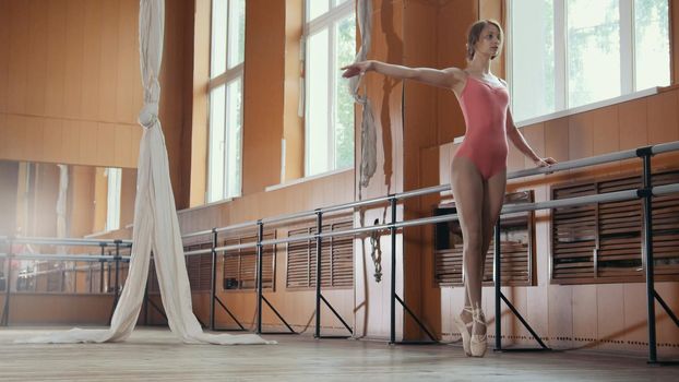 Model girl in pink dress and pointe shoes ballerina practicing in the Studio, wide angle view