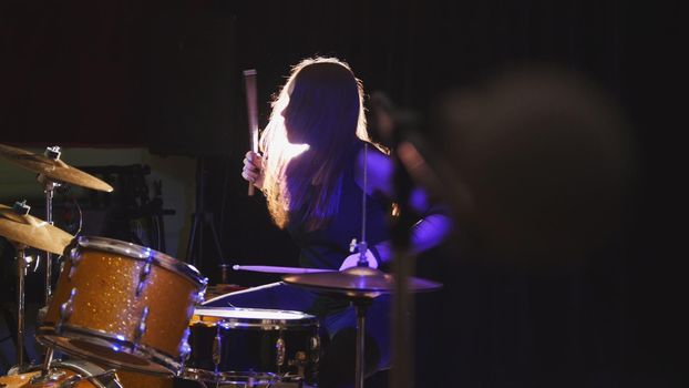 Girl rock musician - female drummer performing, telephoto