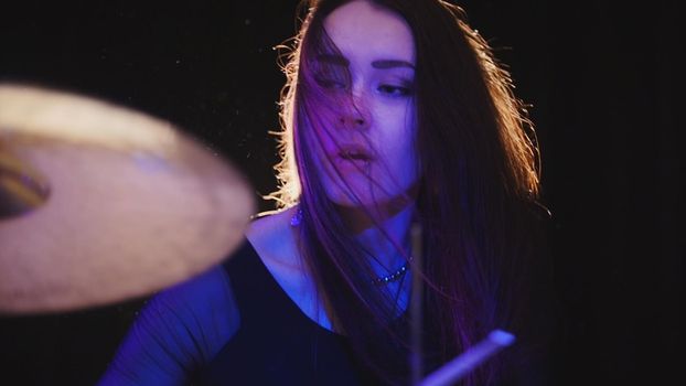 Emotional girl drummer, attractive youngblack hair model plays the drums, telephoto