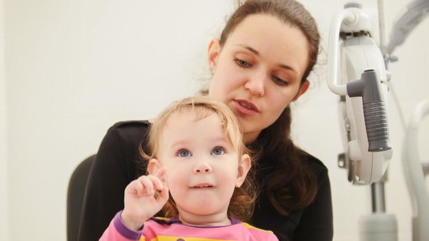 Mother and doughter in ophthalmologist room, horizontal