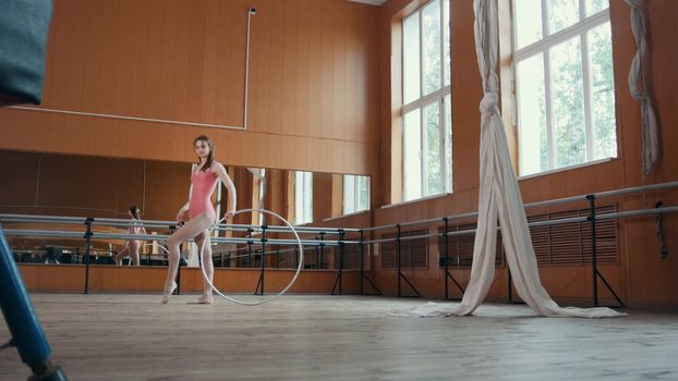 A young girl gracefully performs acrobatics with gymnastic hoop, close up