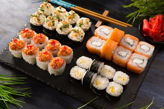 Set of sushi rolls with wasabi and ginger on a black background. Japanese oriental cuisine .