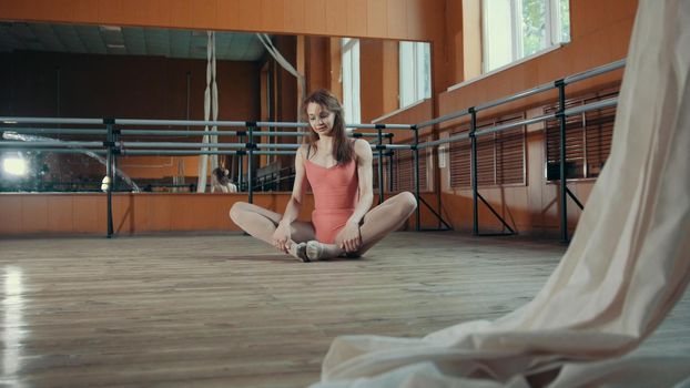 Model girl in pink dress and pointe shoes ballerina practicing in the studio, wide angle