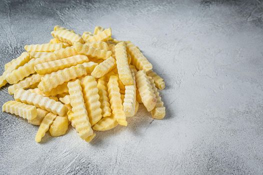 Frozen Crinkle French fries potatoes sticks. White background. Top view. Copy space.