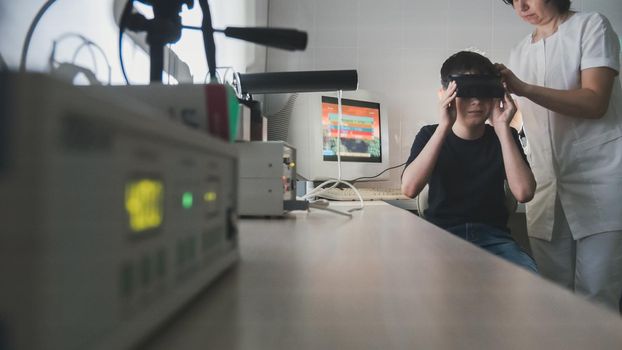 Ophthalmology doctor checks the child's vision with the help of stereovideo virtual reality glasses, wide angle