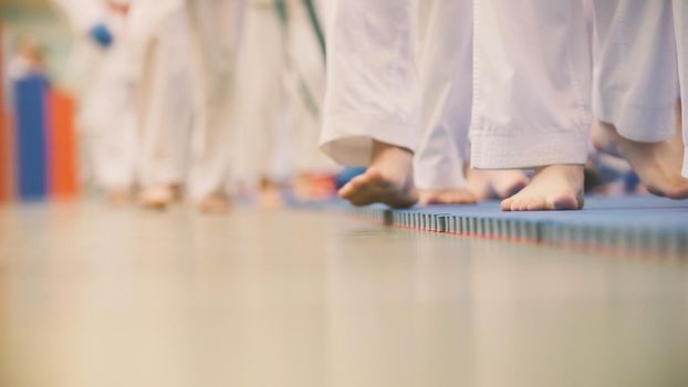 Karate training - teenagers in kimono runs on tatami in the gym, de-focused