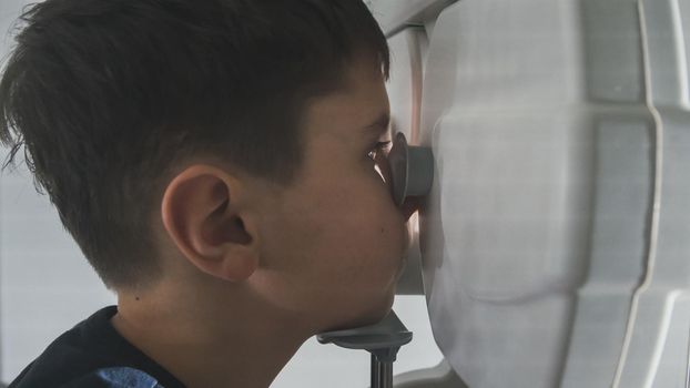Close up view of boy checks eye vision in ophthalmology clinic, close up