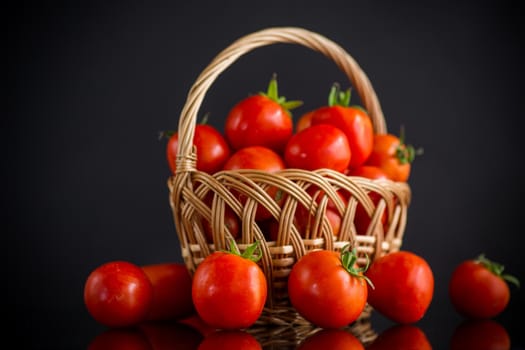 fresh ripe red tomatoes in basket isolated on black background