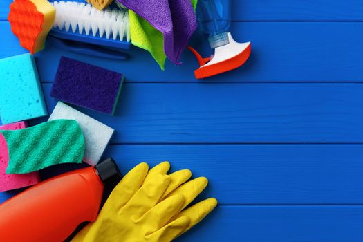 Household cleaning supplies on blue wooden background flat lay top view